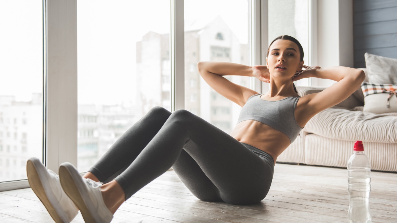 Спортивная девушка качает пресс дома 