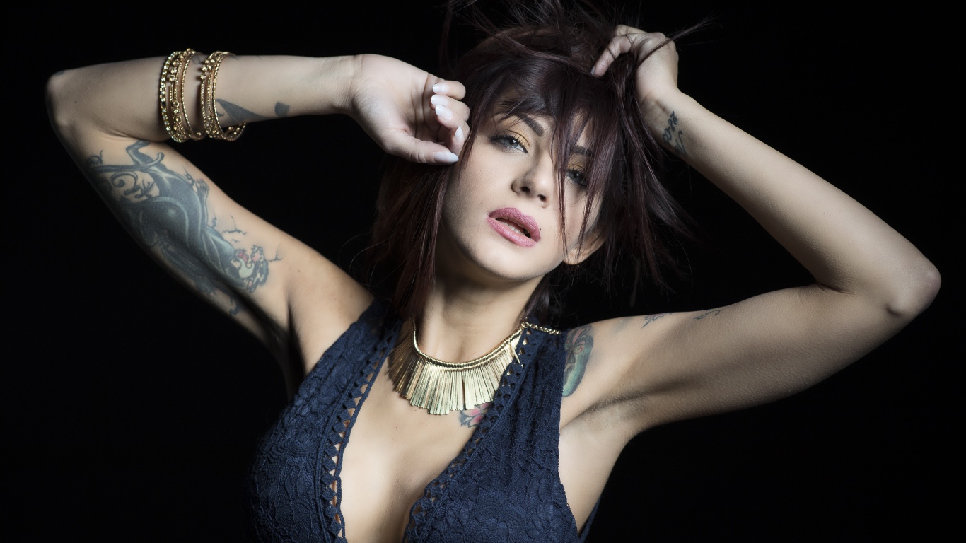 Красивая девушка в черном платье с татуировками на теле 