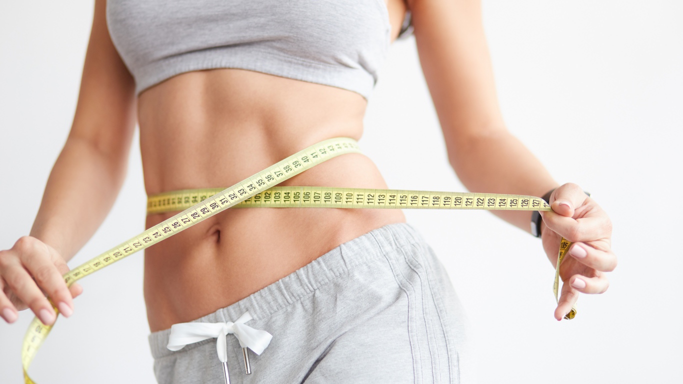 Красивая стройная девушка меряет талию сантиметром 