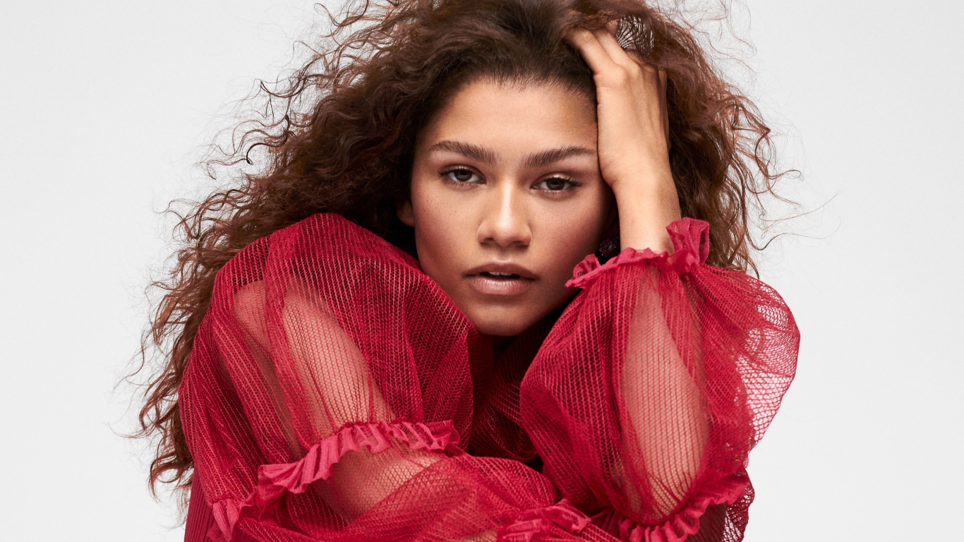 Кареглазая актриса Зендая в красном наряде с рукой в волосах