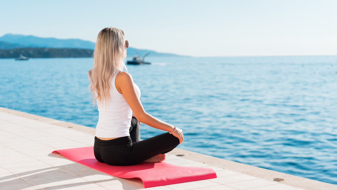 Девушка медитирует на берегу моря 