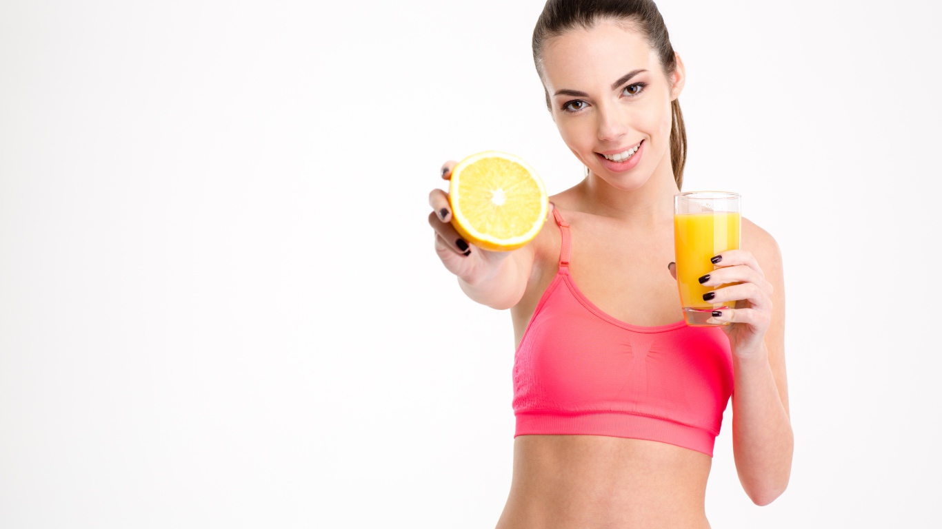 Девушка со стаканом сока и апельсином на белом фоне