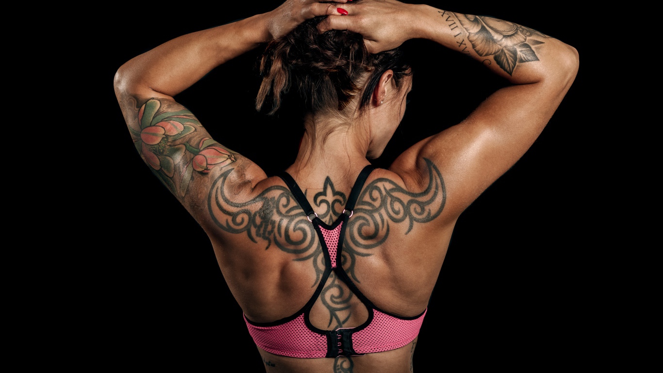 Tattoos on the body of a sports girl on a black background