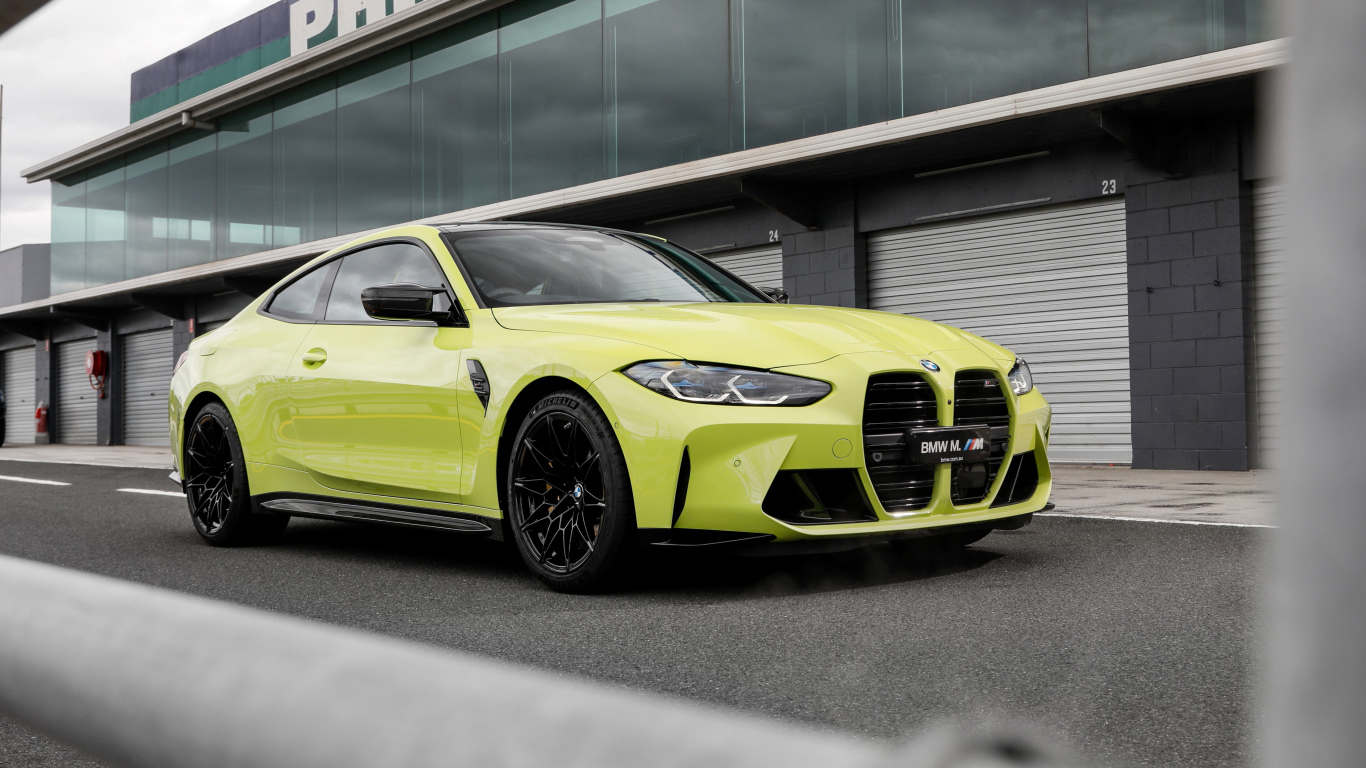 Желтый автомобиль BMW M4 Competition 2021 года у здания