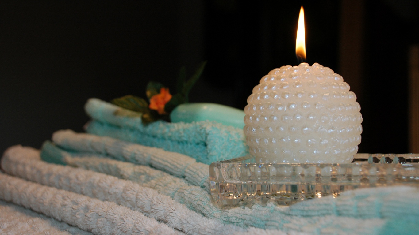 Красивая зажженная свеча с полотенцами
