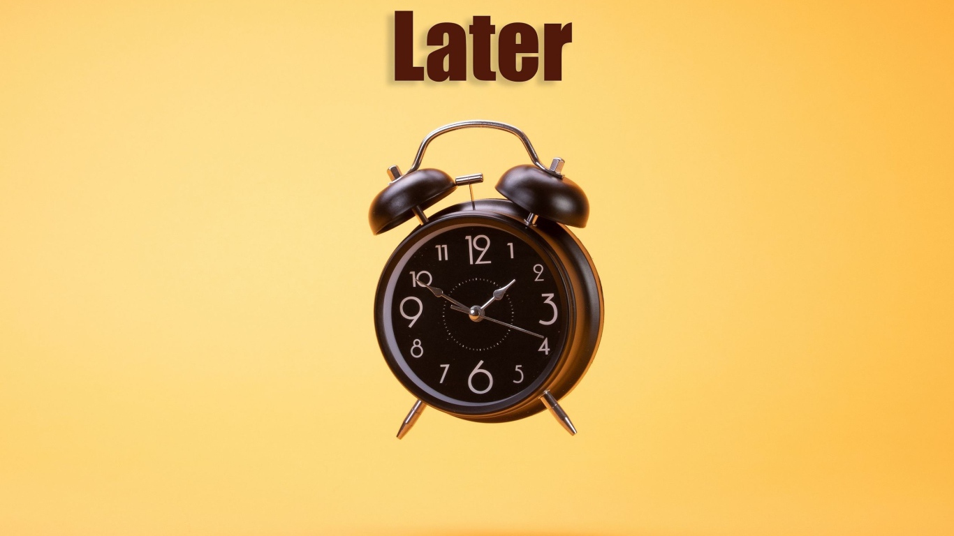 Большой черный будильник на желтом фоне 