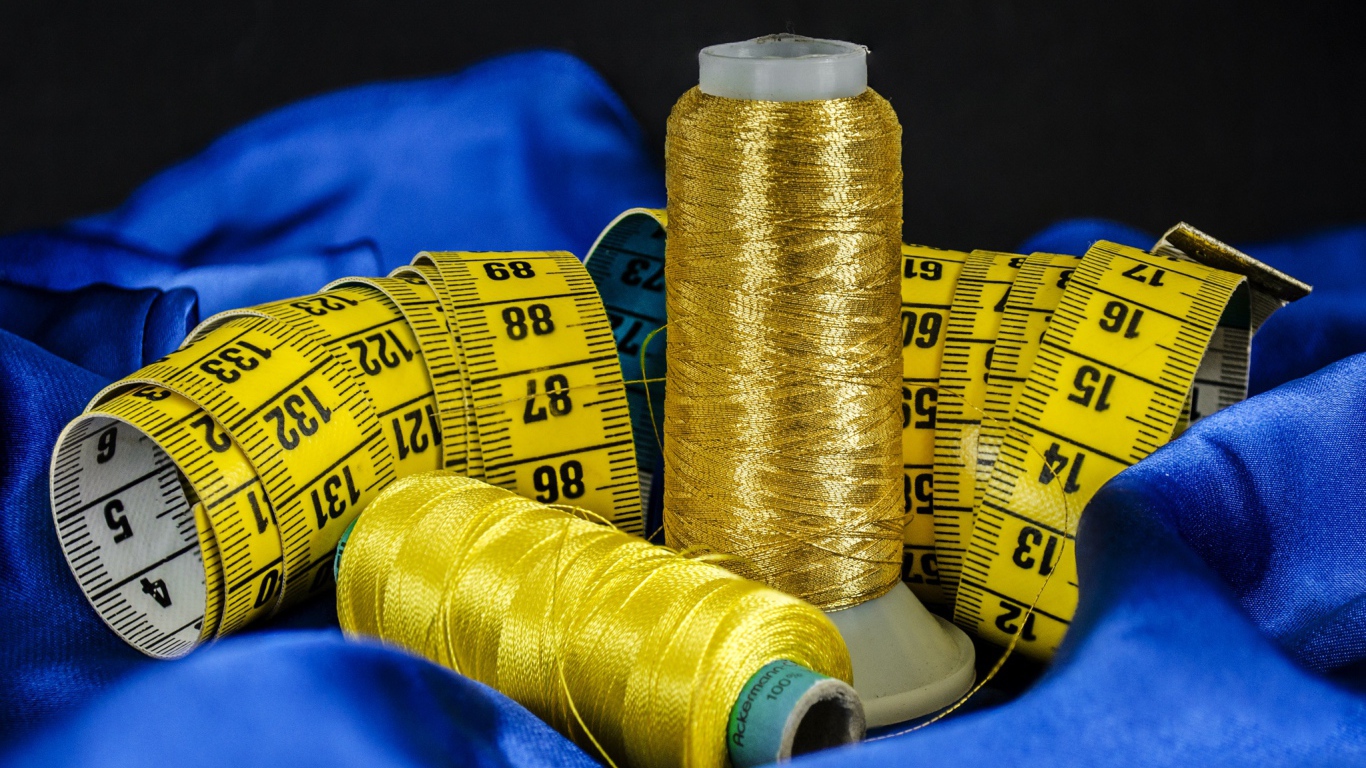 Золотые нитки и сантиметр на голубой ткани 