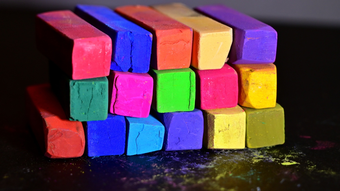 Разноцветные мелки для школы на черной поверхности 