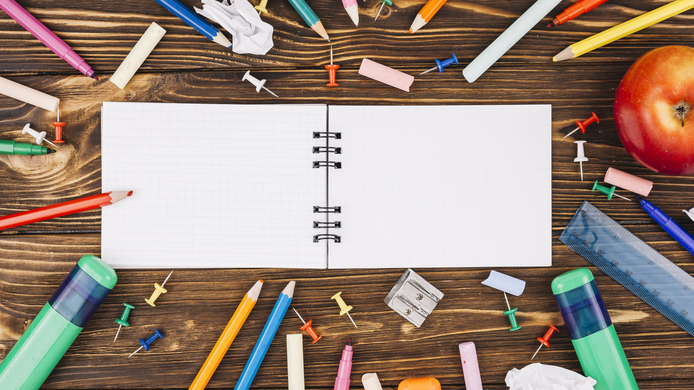 Открытый блокнот с ручками  на столе 