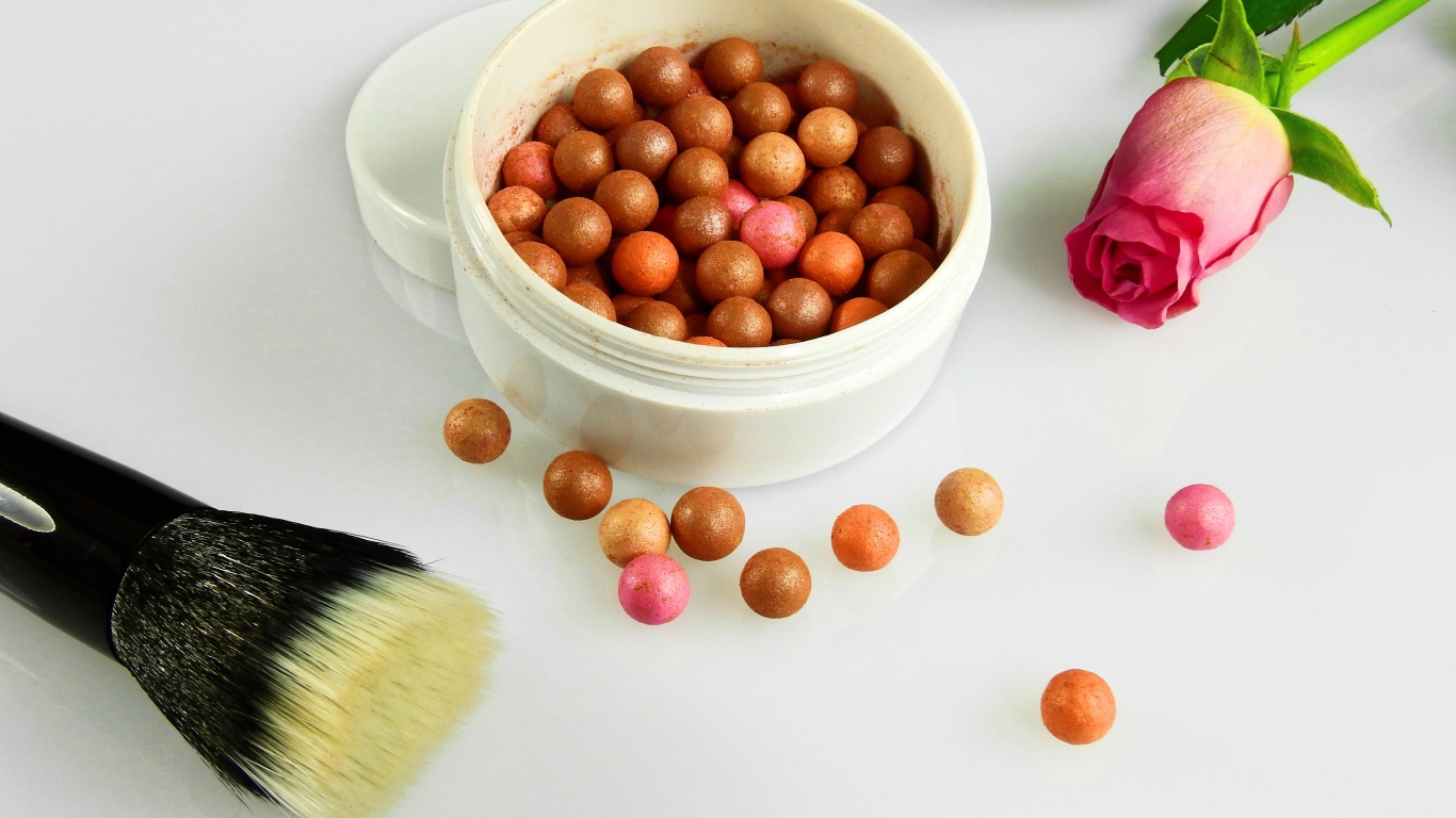 Шариковая пудра на белом фоне с кистью и розой