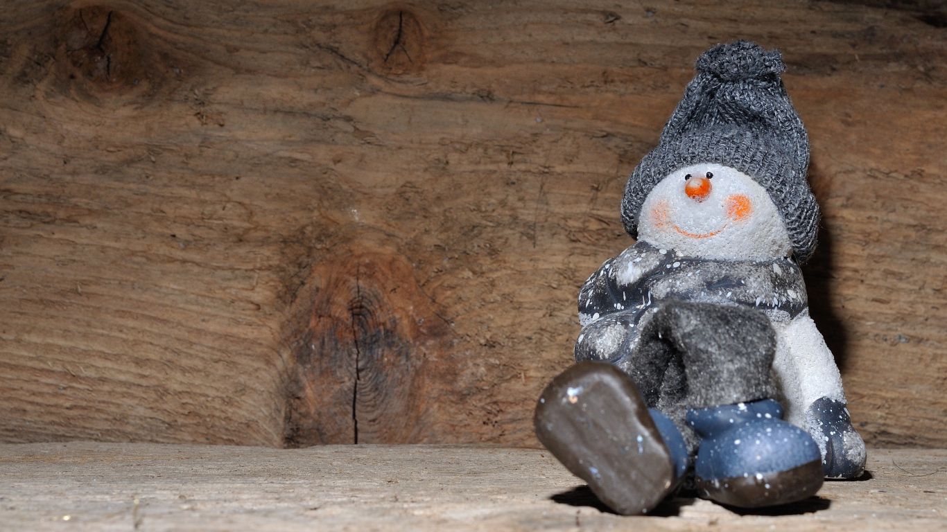 Фигурка снеговик у деревянной стены