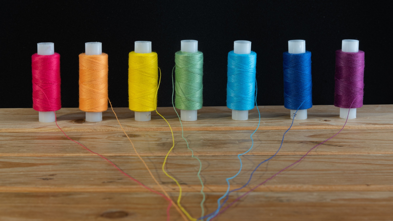 Катушки с разноцветными нитками на черном фоне 