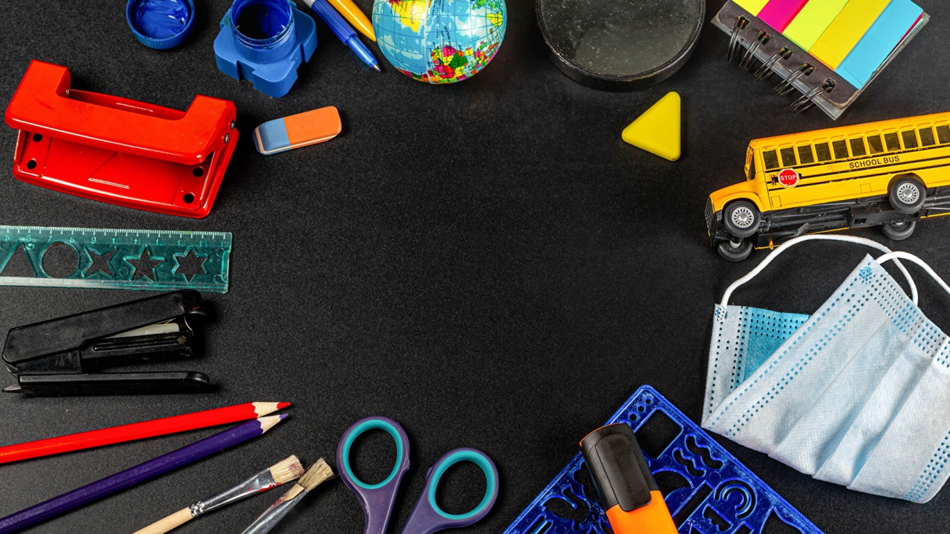 Канцелярские предметы, игрушки и маска на черном столе 