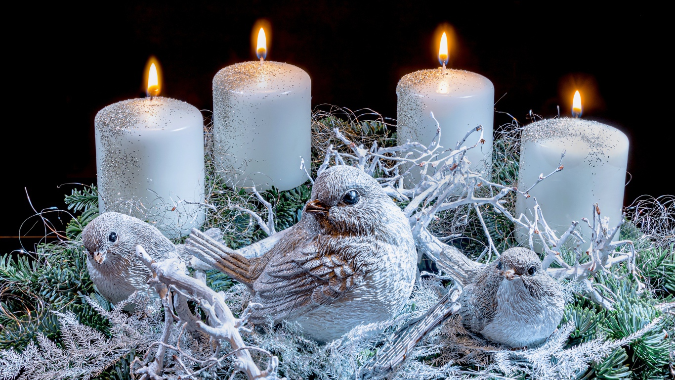 Три зажженные свечи со статуэтками птицами 