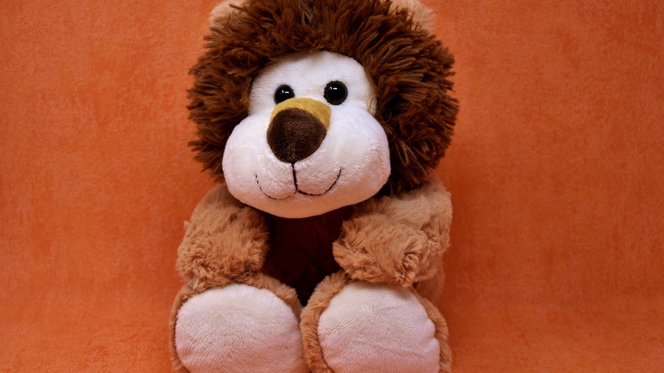 Игрушечный лев на фоне стены