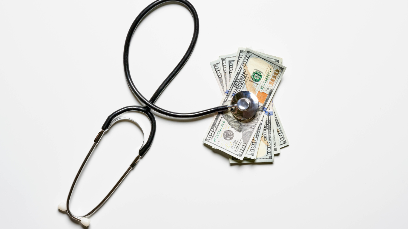 Фонендоскоп с долларами на белом фоне