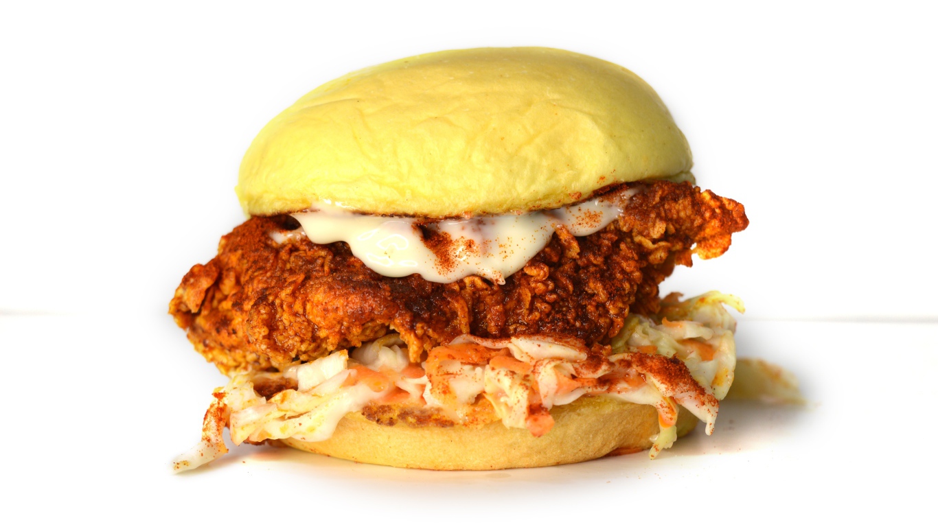 Большой куриный бургер с соусом на белом фоне