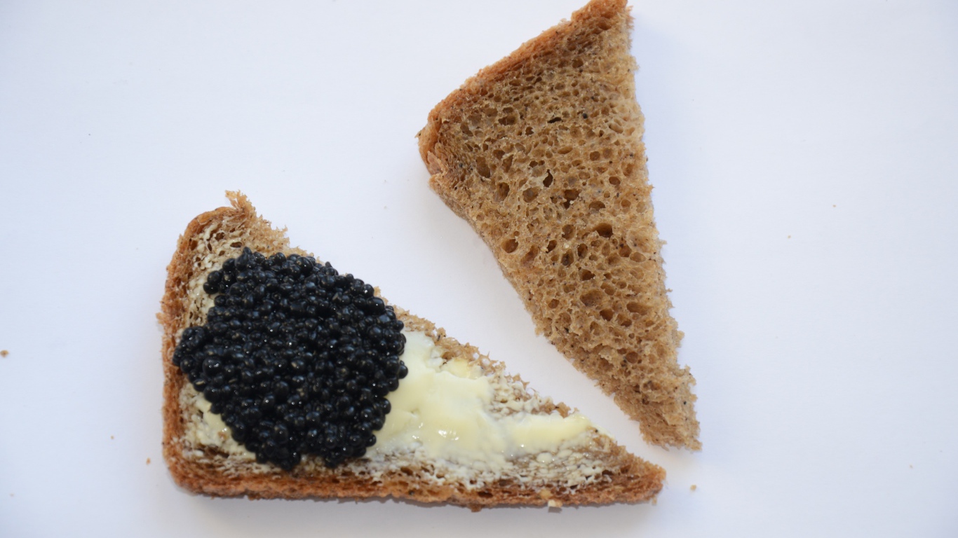 Бутерброды из черного хлеба с черной икрой на сером фоне