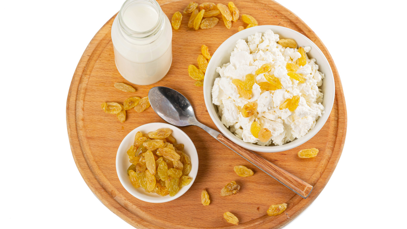 Творог с изюмом и молоком на доске на белом фоне 