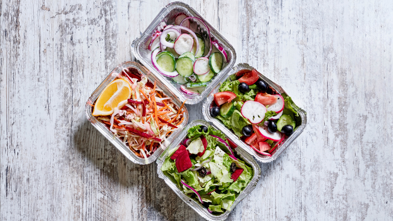 Разные овощные салаты в тарелках на сером столе 