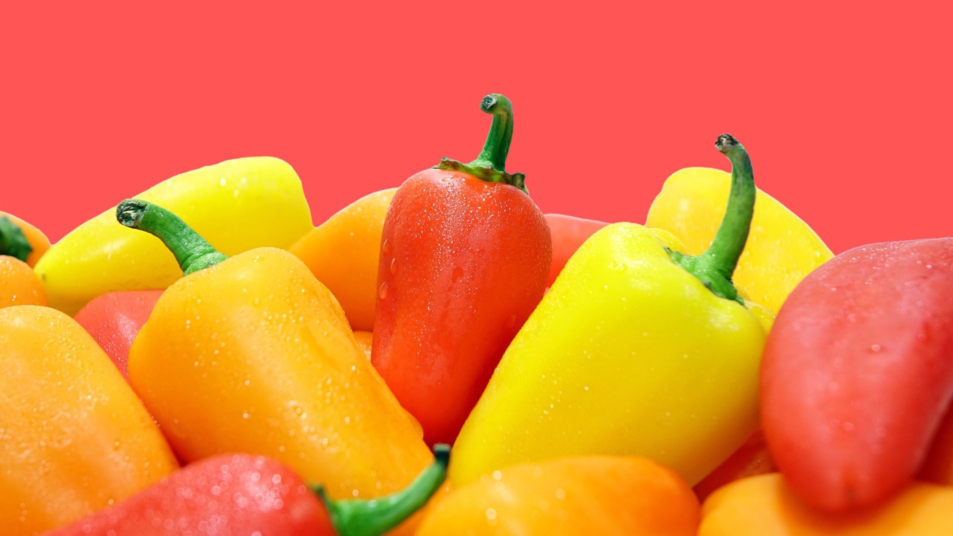 Красный и желтый перец на розовом фоне 