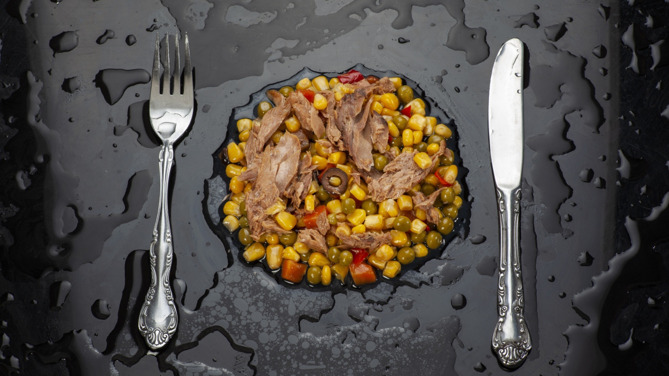 Овощи с мясом и столовыми приборами на черной поверхности