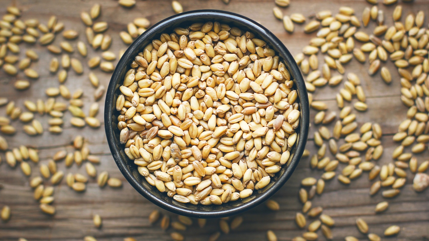 Зерна пшеницы в черной кружке на столе 