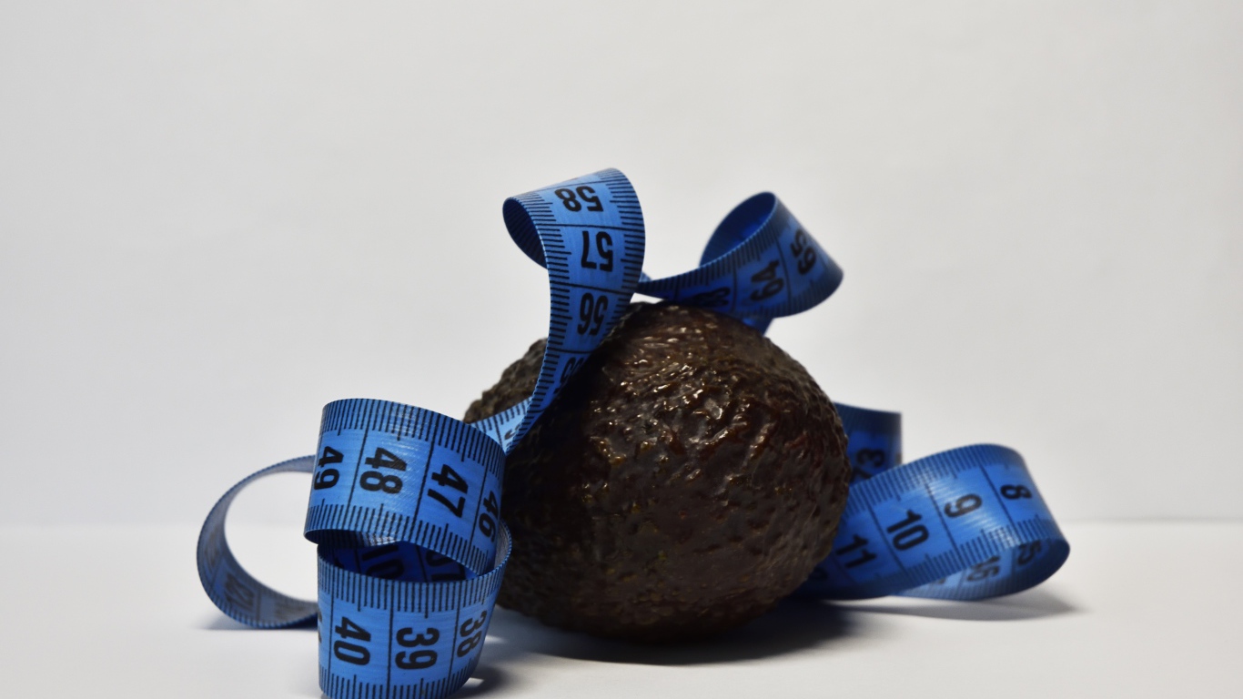 Авокадо с сантиметром на сером фоне