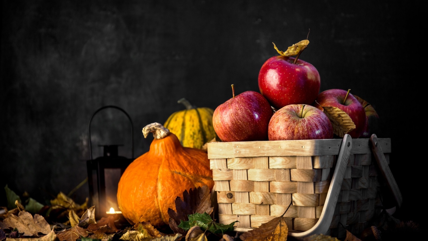 Корзина красных яблок на столе с тыквой