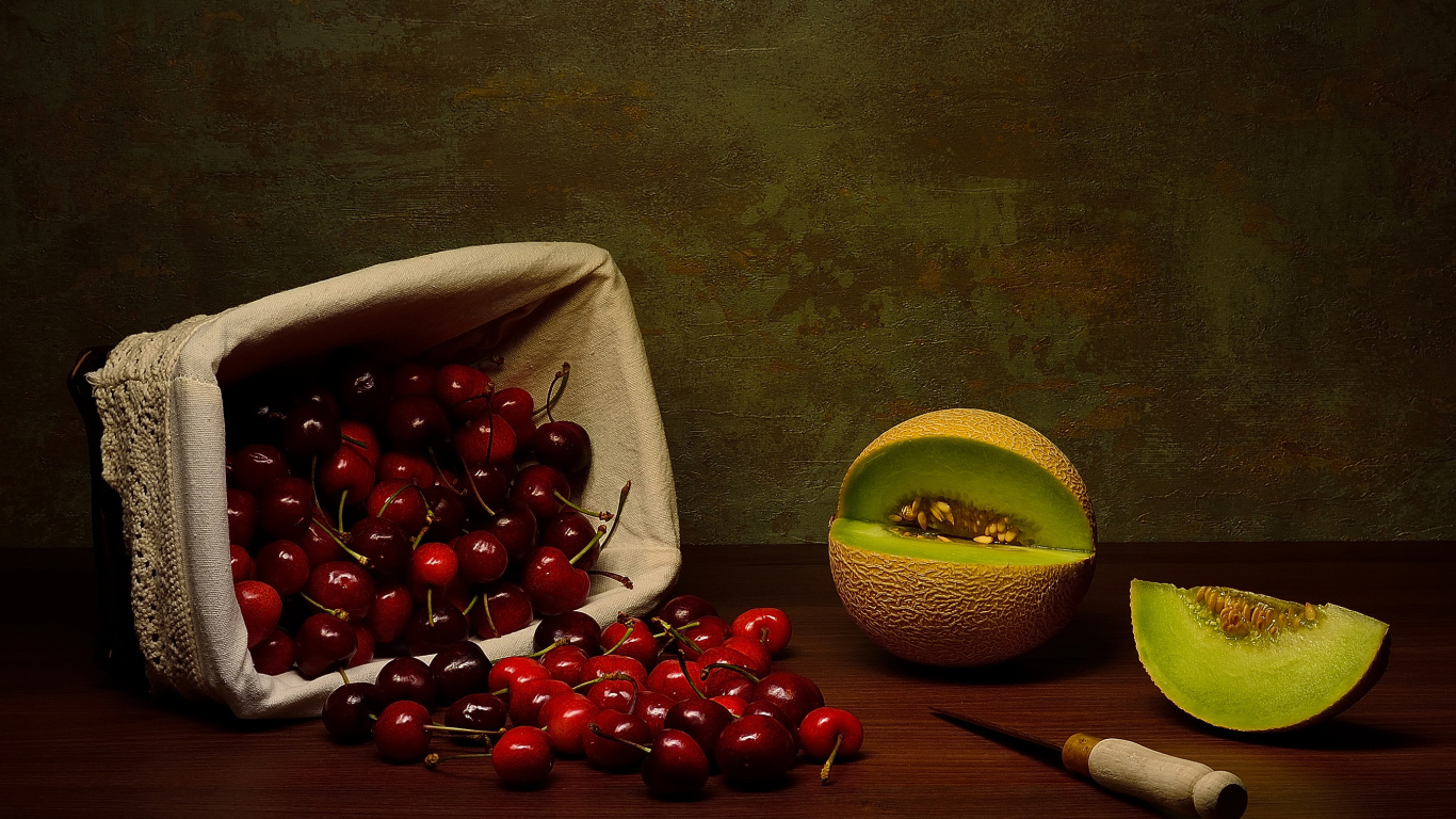 Корзина с черешнями на столе с дыней