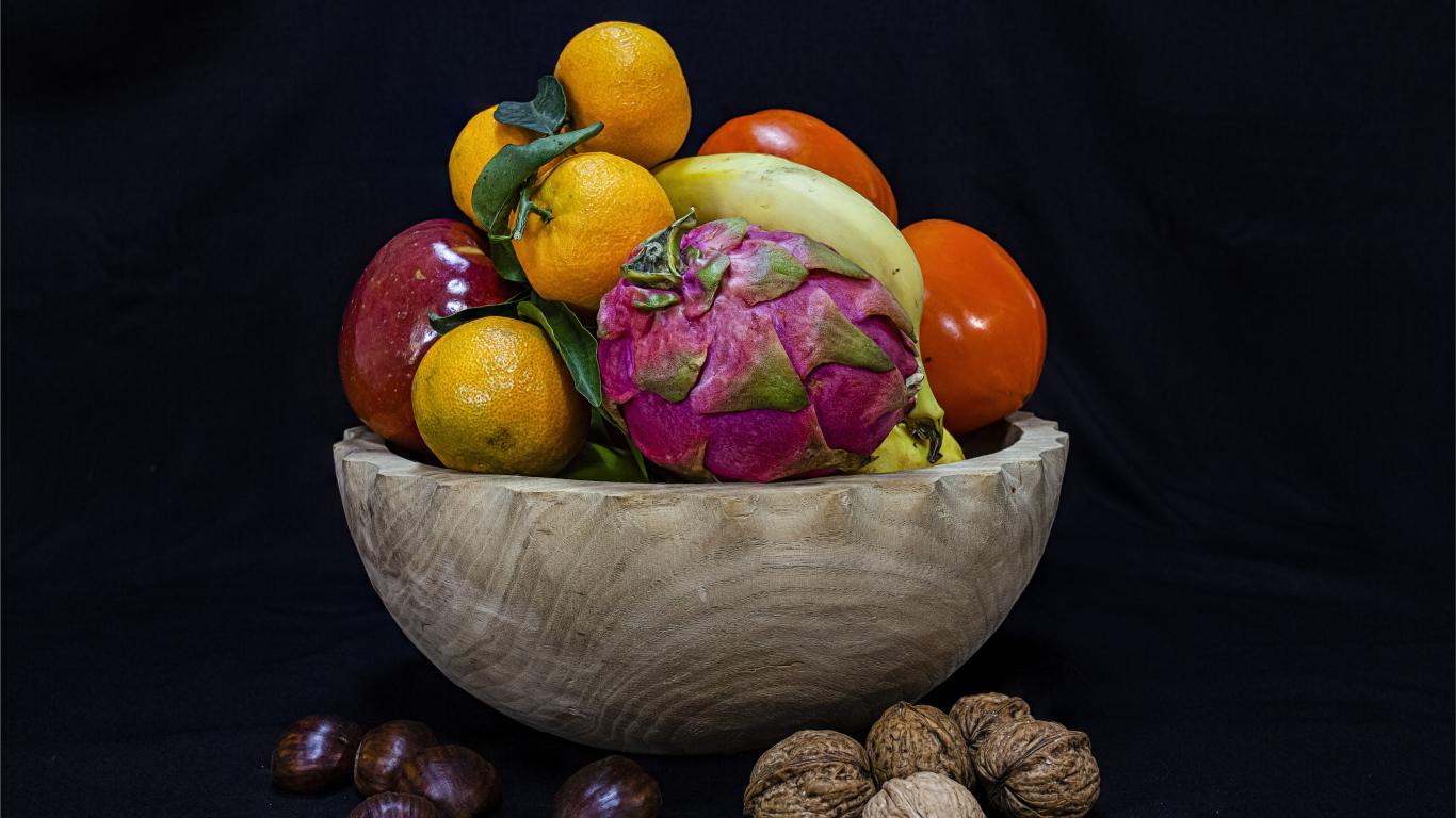 Цитрусовые фрукты в деревянной миске на черном фоне