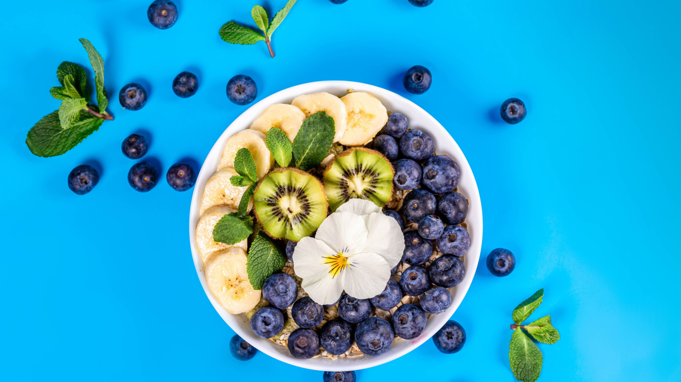 Хлопья с кусочками банана, черникой и киви на голубом фоне 