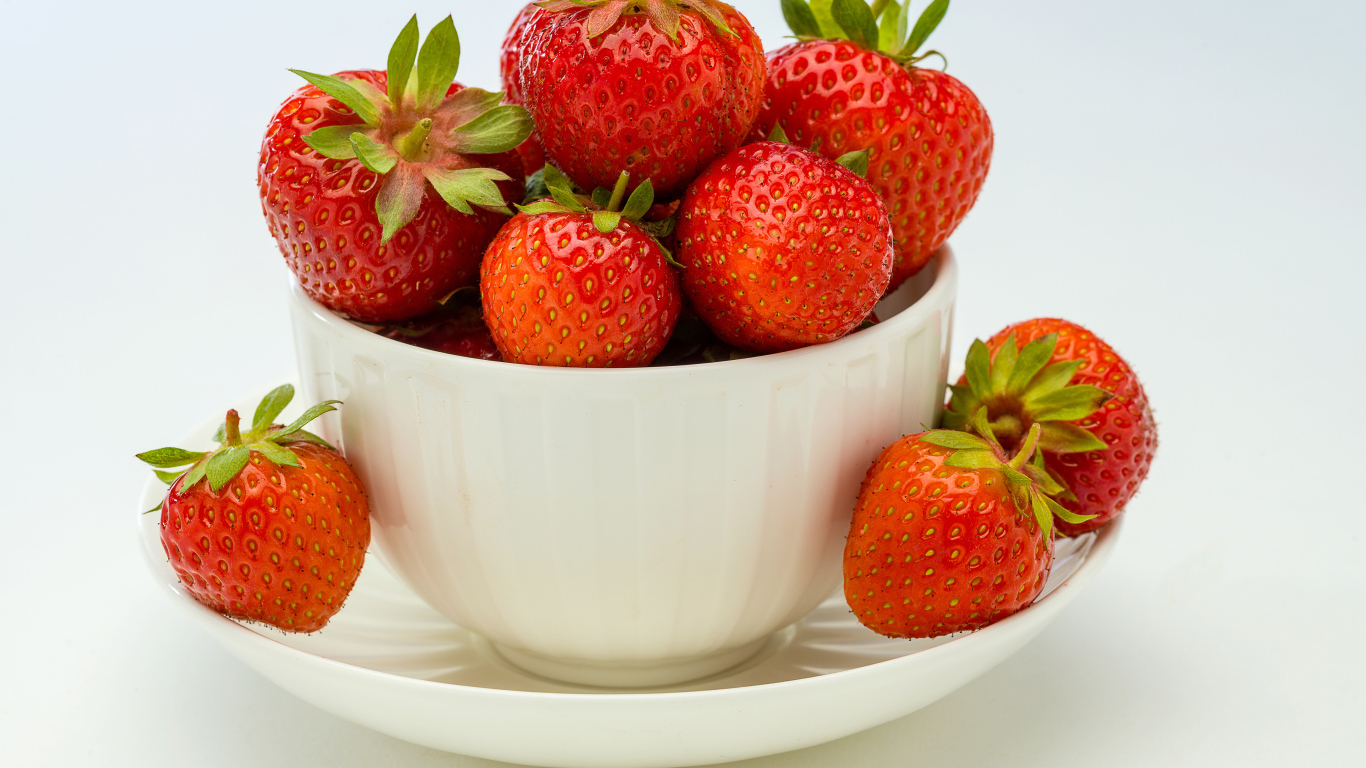 Спелая красная клубника в белой миске с блюдцем