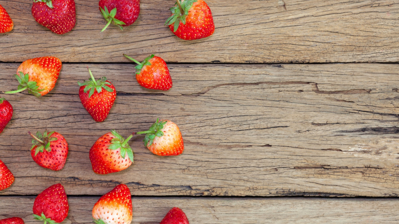 Спелая красная клубника лежит на деревянном столе