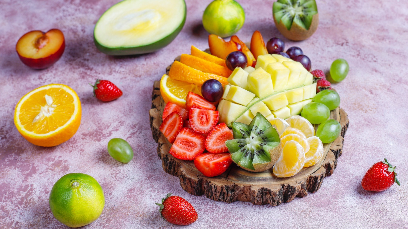 Нарезанные фрукты и ягоды на деревянной доске 