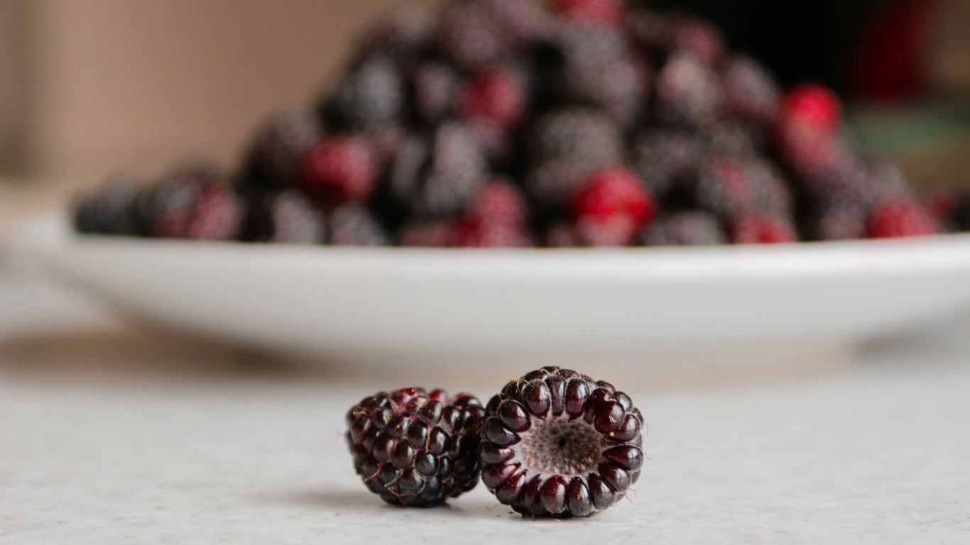 Две ягоды спелой ежевики на столе 