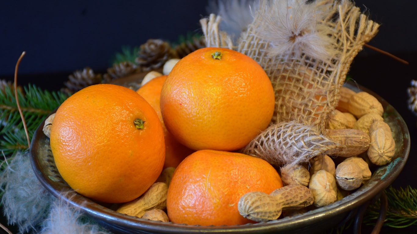 Желтые апельсины с арахисом  на тарелке