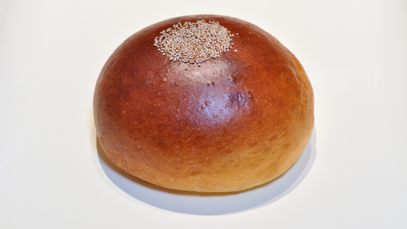 Аппетитная круглая булочка на сером фоне