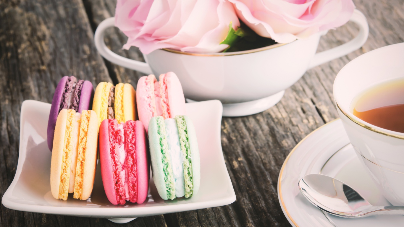 Десерт макарон на столе с чаем и цветами розы