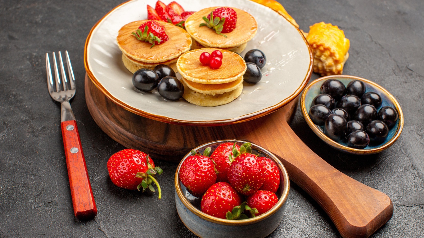 Оладьи с виноградом и клубникой на тарелке 