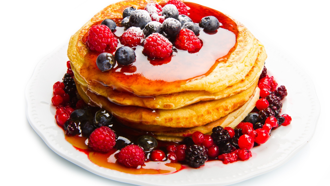 Оладьи с медом и ягодами малины и черники на белом фоне