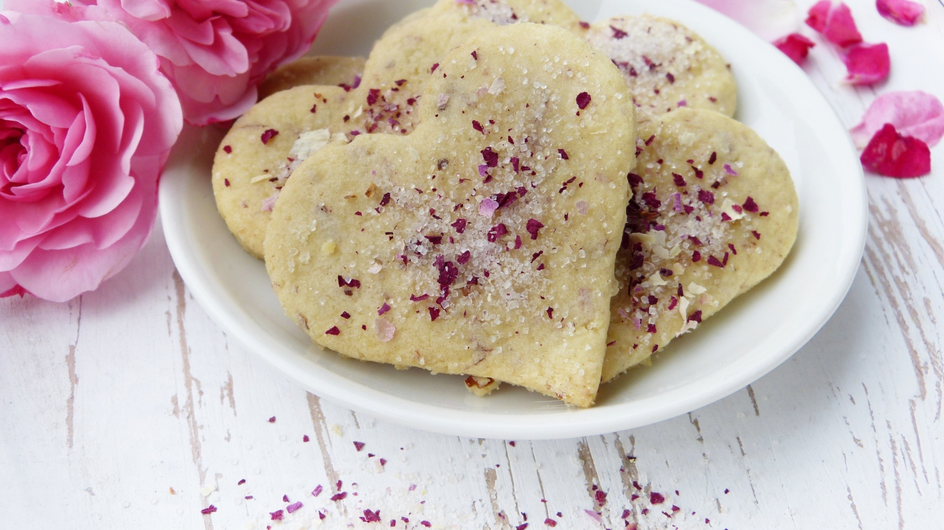 Песочное печенье в форме сердца в белой тарелке с цветами