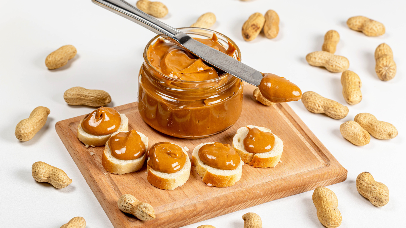 Ореховая паста на столе с батоном и арахисом