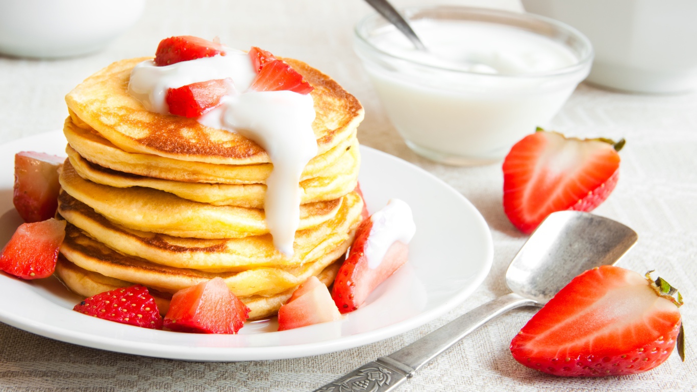 Оладьи с клубникой и сметаной на столе