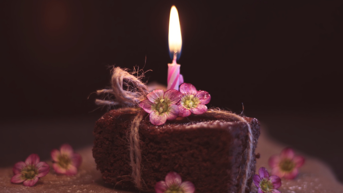 Кусок торта на столе с розовыми цветами и свечкой