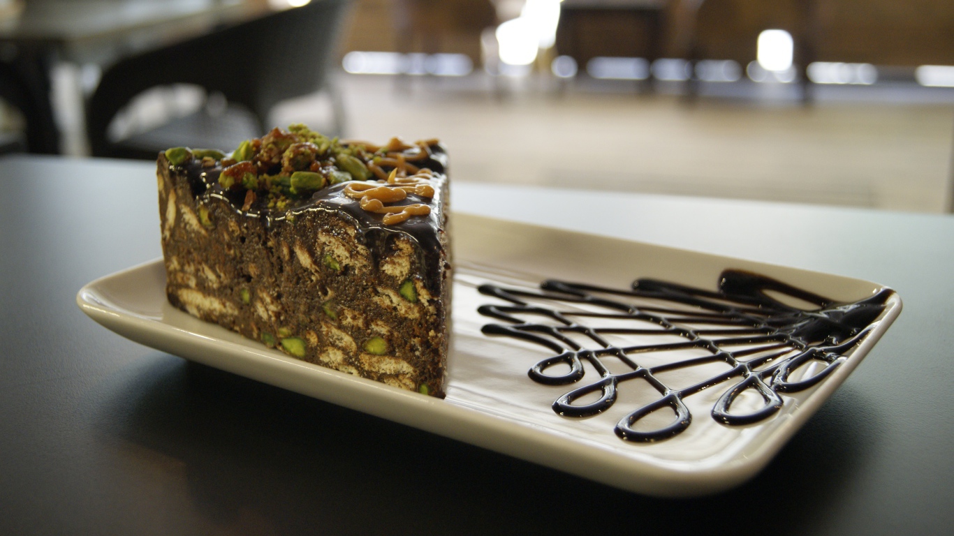 Кусок торта с фисташками на белой тарелке 