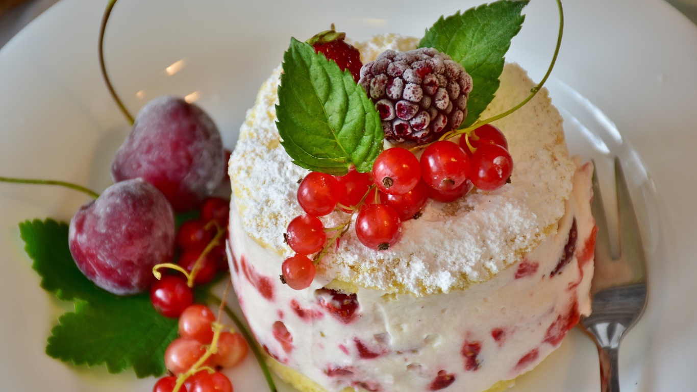 Пирожное со взбитыми сливками украшено ягодами