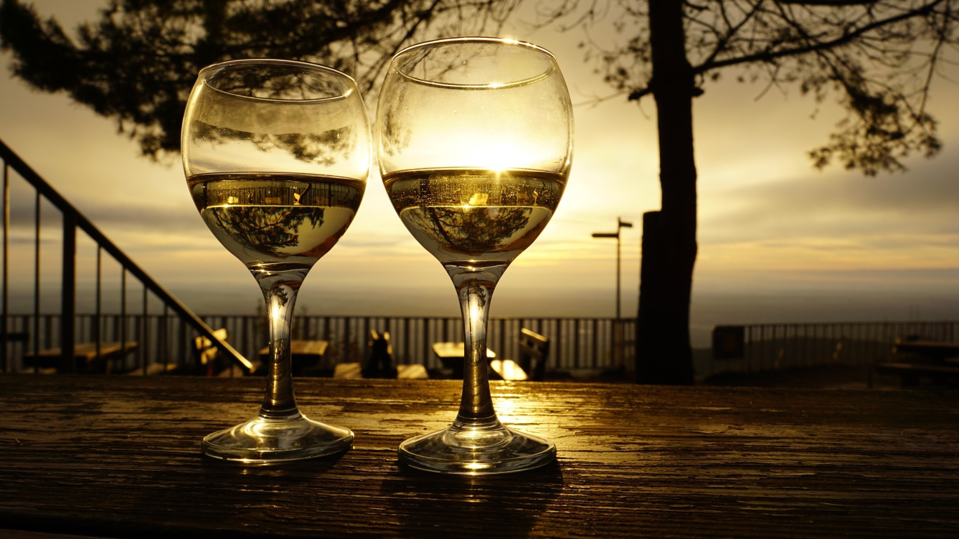 Два бокала белого вина на столе в лучах солнца