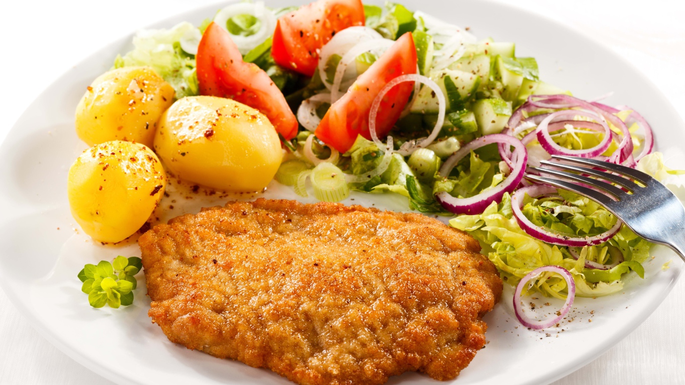 Отбивная с курицы на тарелке с картофелем и овощами 