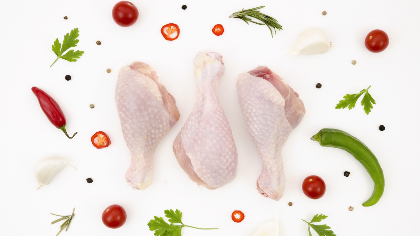 Свежие куриные бедра с перцем и помидорами на белом фоне 